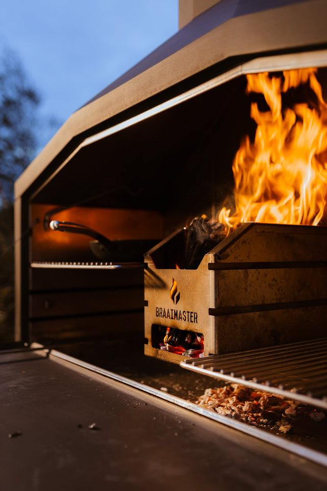 Braaimaster in deschemering met brandendvuur en skillet op het rooster