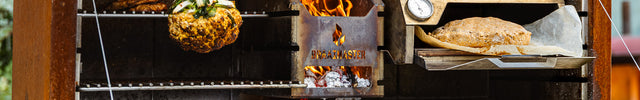 Braaimaster Duo Corten, geopend, vooraanzicht met vuur in de firebok en een braaioven op het rooster plus gegrilde bloemkool aan de haak
