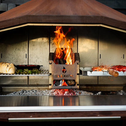 Braaimaster Duo Corten vooraanzicht, klep open met RVS inlay, brandend met op de roosters brood en spiesen