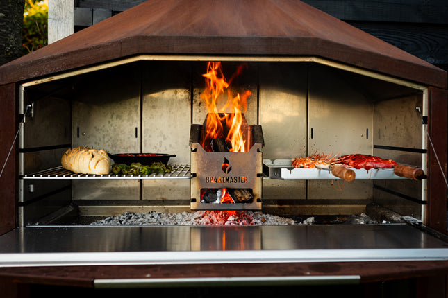 Braaimaster Duo Corten vooraanzicht, klep open met RVS inlay, brandend met op de roosters brood en spiesen