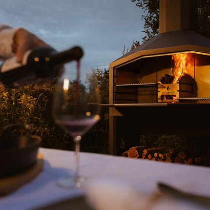 Braaimaster Duo Black brandend op een terras wijn wordt ingeschonken op de voorgrond