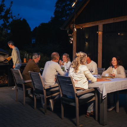 Braaimaster Duo Black op een terras in de schemering met een eettafel vol mensen ervoor
