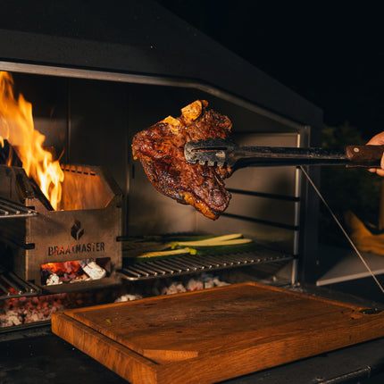 Braaimaster Duo Black in de schemering brandend met op de voorgrond een sappige porterhouse of T-bone steak