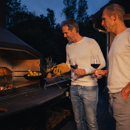 Braaimaster Duo Black brandend met 2 mannen ervoor met een glaswijn die krieltjes bakken in een skillet