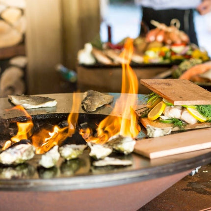 OFYR Classic 85 grillring met brandend vuur en rookplankjes en oesters op de plancha ring