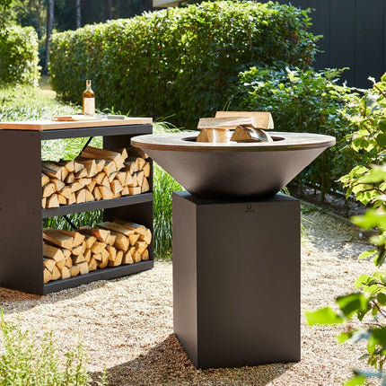 OFYR Heritage Classic 100 in tuin met OFYR wood storage op de achtergrond