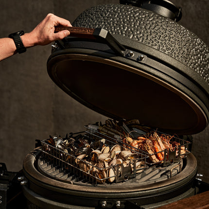 The Bastard kamado VX Large met geopende deksel en op het rooster mandjes met fruit de mere