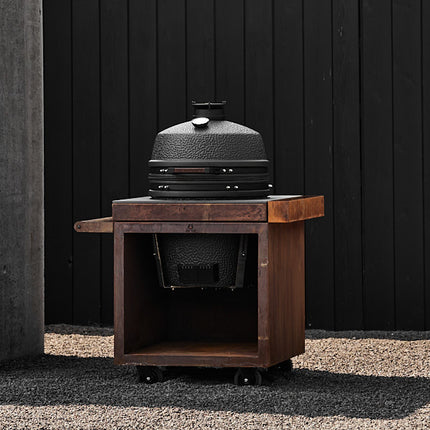 The Bastard kamado VX Large Solo ingebouwd in een corten stalen tafel geplaatst in het grind